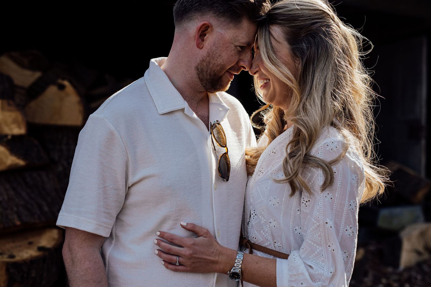 A romantic couple sharing an intimate moment together in white attire against a dark background.