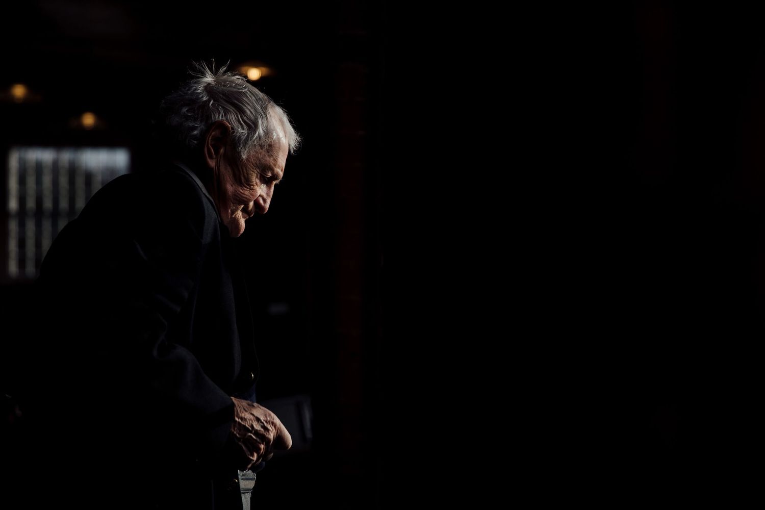 Dramatic side-lit portrait in dark setting with moody atmosphere.