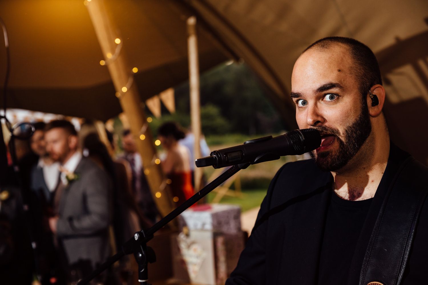 Live band performing at a tipi wedding reception with professional lighting setup.