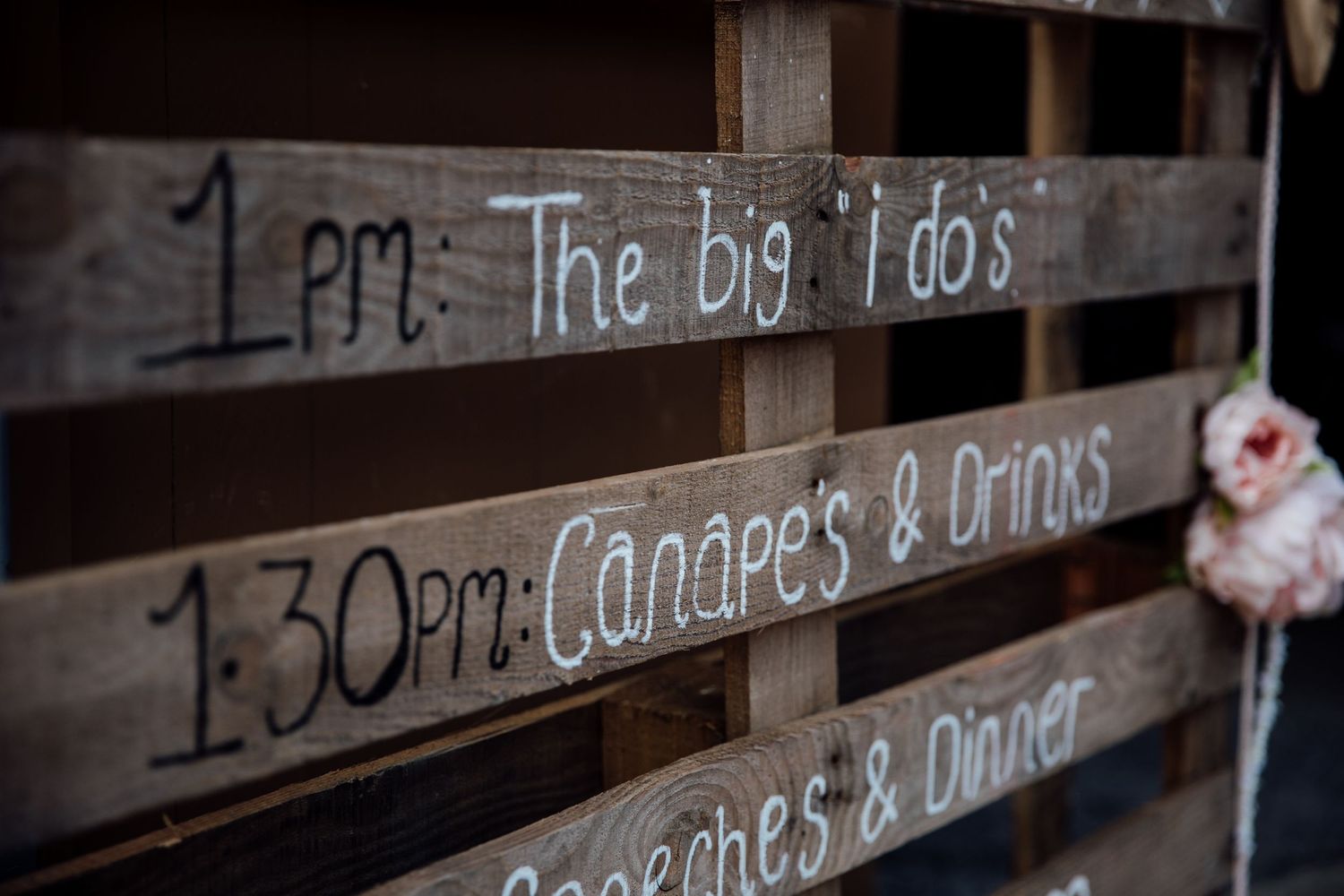 Rustic wooden signs with handwritten text displayed at a wedding venue.