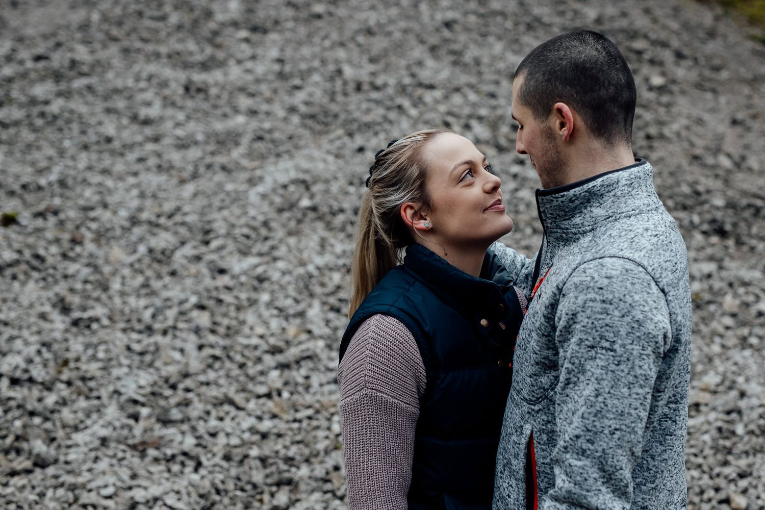 A joyful moment shared between a couple wearing warm winter clothing against a rocky backdrop.