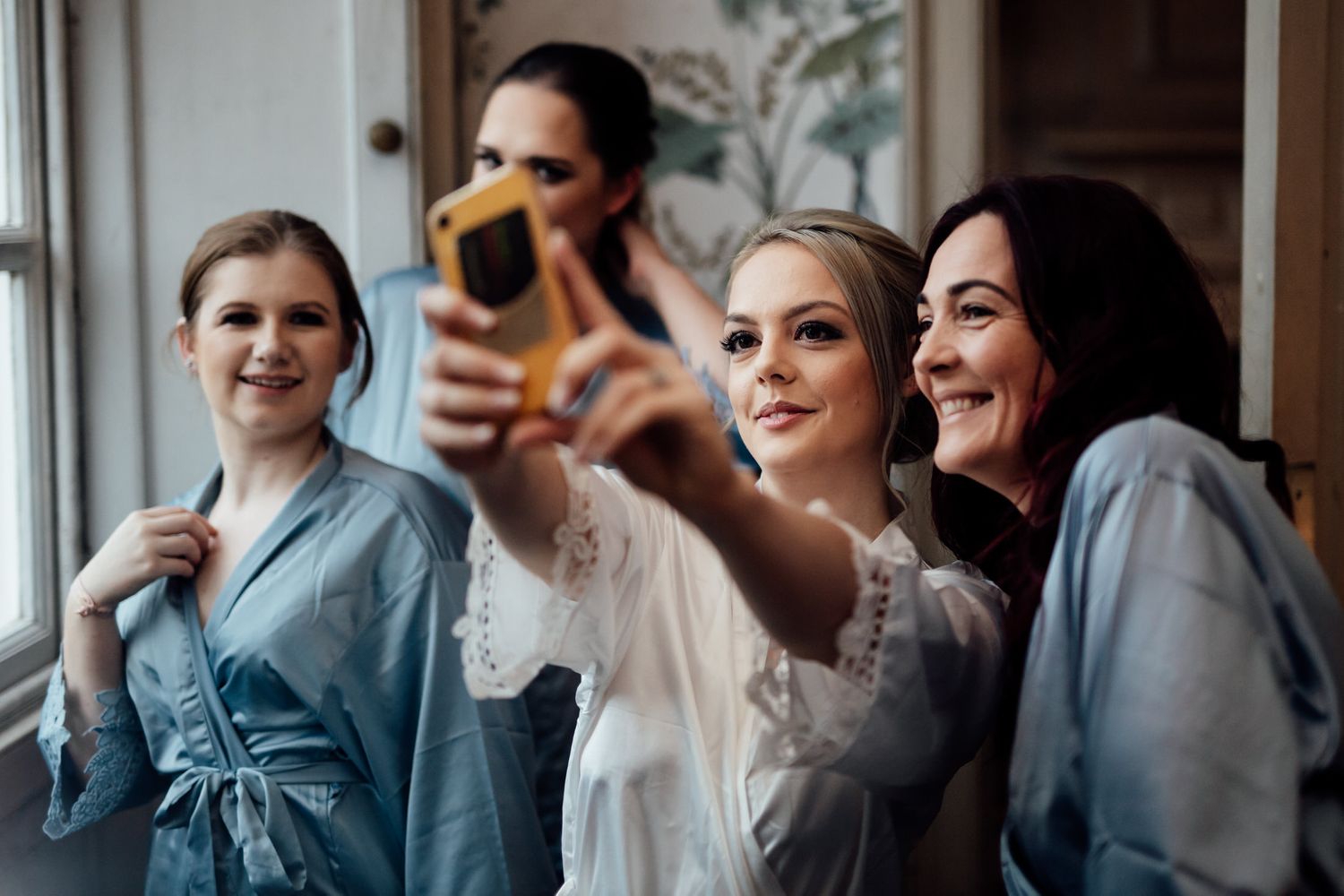 Wedding preparation scene with bridesmaids in gray dresses getting ready together.