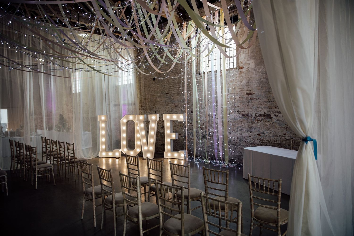 Wedding venue with illuminated LOVE sign and crystal chandeliers.