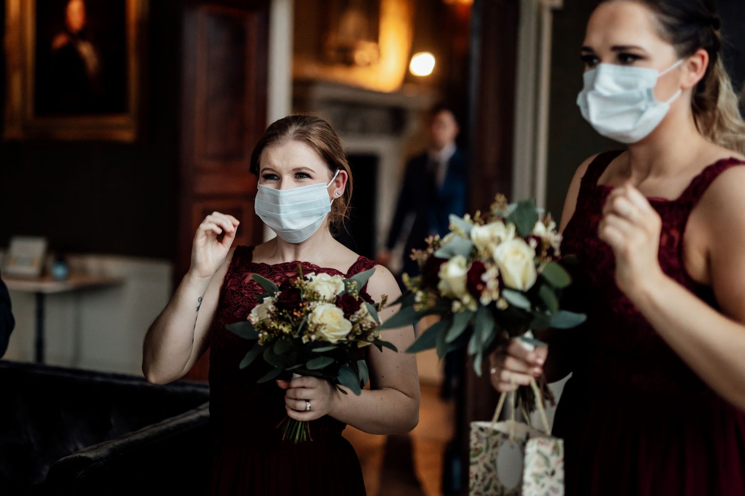 Wedding party members wearing protective masks while holding floral bouquets.