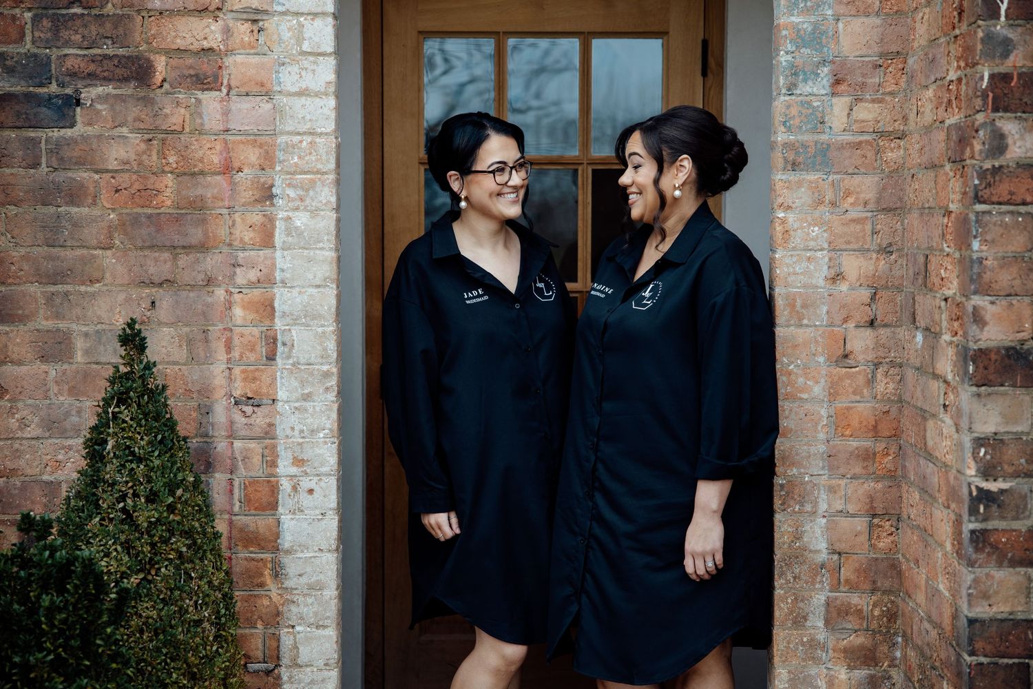 Two people share an intimate moment against a rustic brick wall backdrop during a wedding photoshoot.