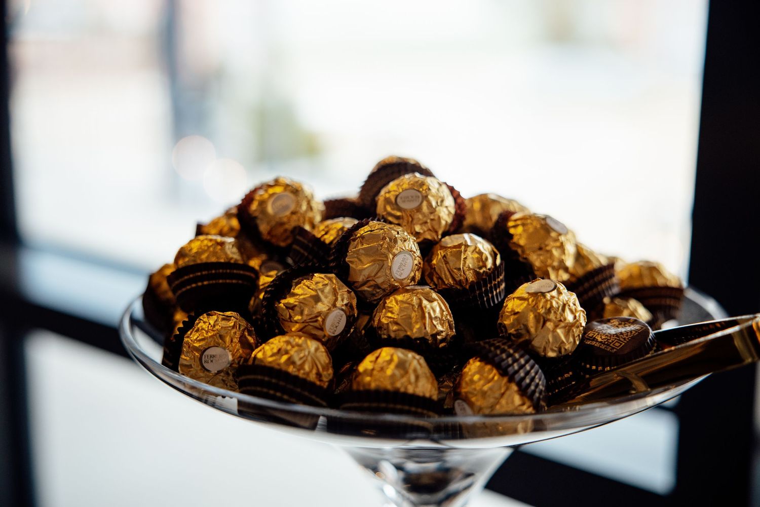 Chocolate truffles arranged on elegant glass serving platters at an upscale event.