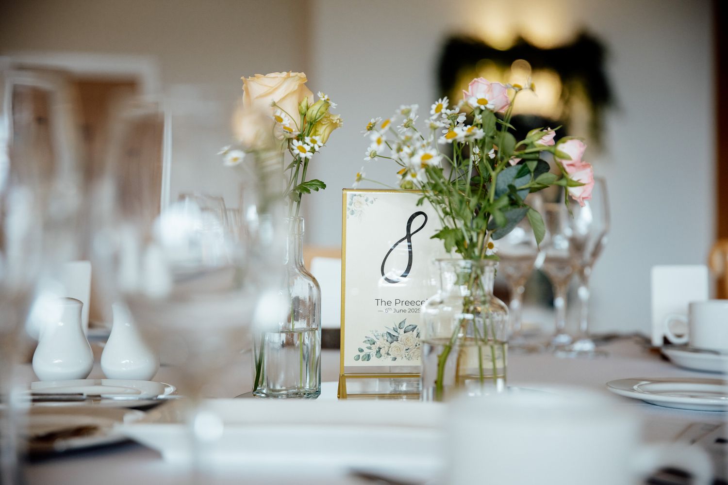 Elegant wedding reception table with delicate floral centerpieces and glassware.