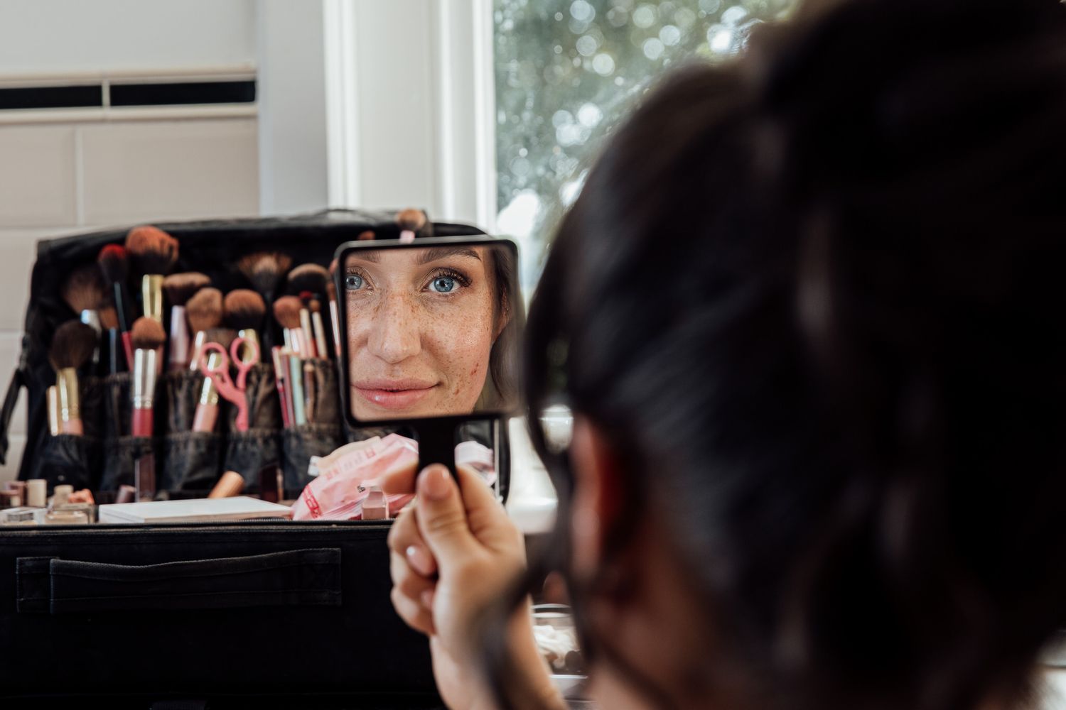 A reflection in a makeup mirror shows wedding preparation activities.