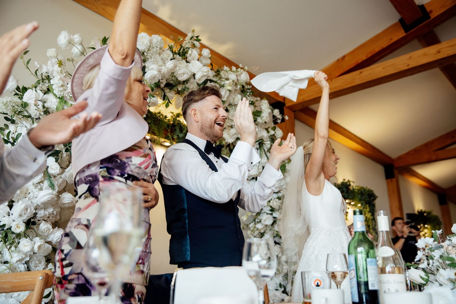 Wedding reception dance floor moments with elegant white floral decorations and wooden beams.