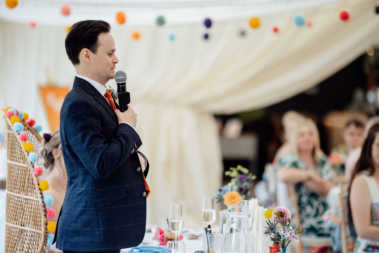 Wedding reception tent decorated with colorful paper lanterns and white draping.
