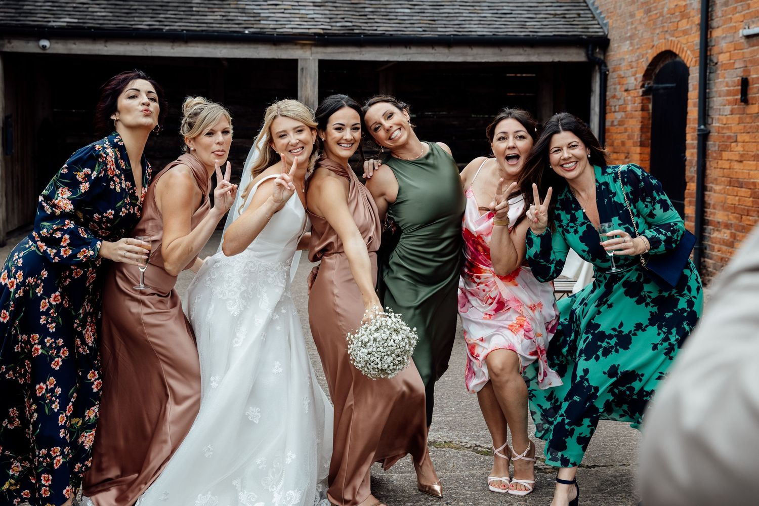Joyful wedding party celebration outside brick building with natural lighting.