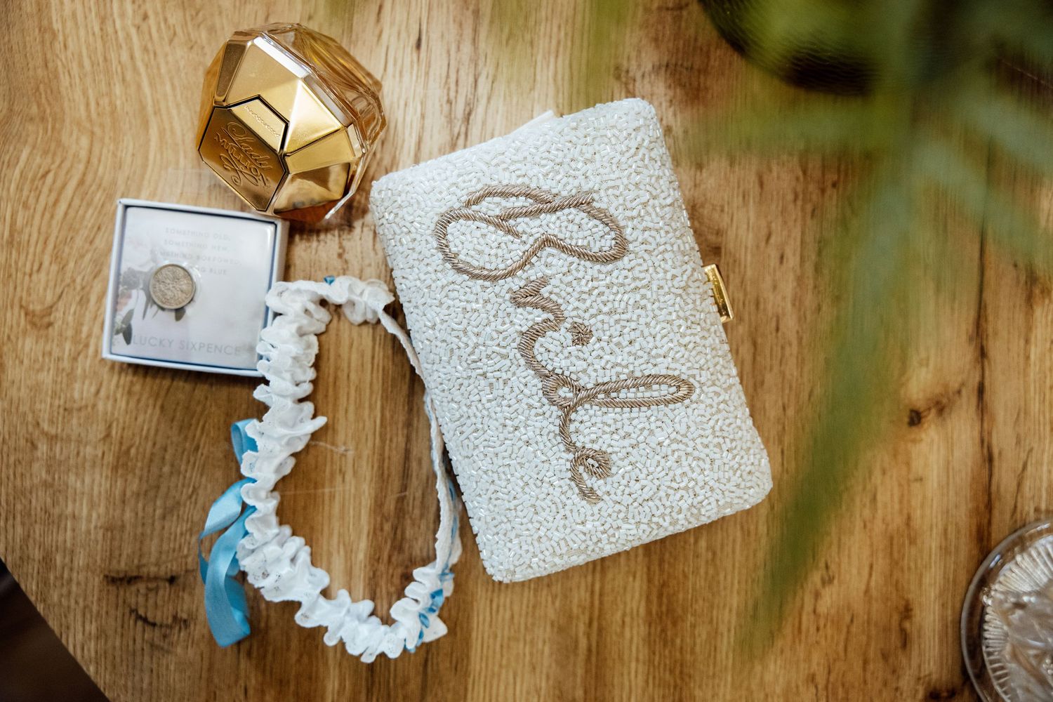 Wedding details with gold rings and delicate lace patterns on wooden surface.