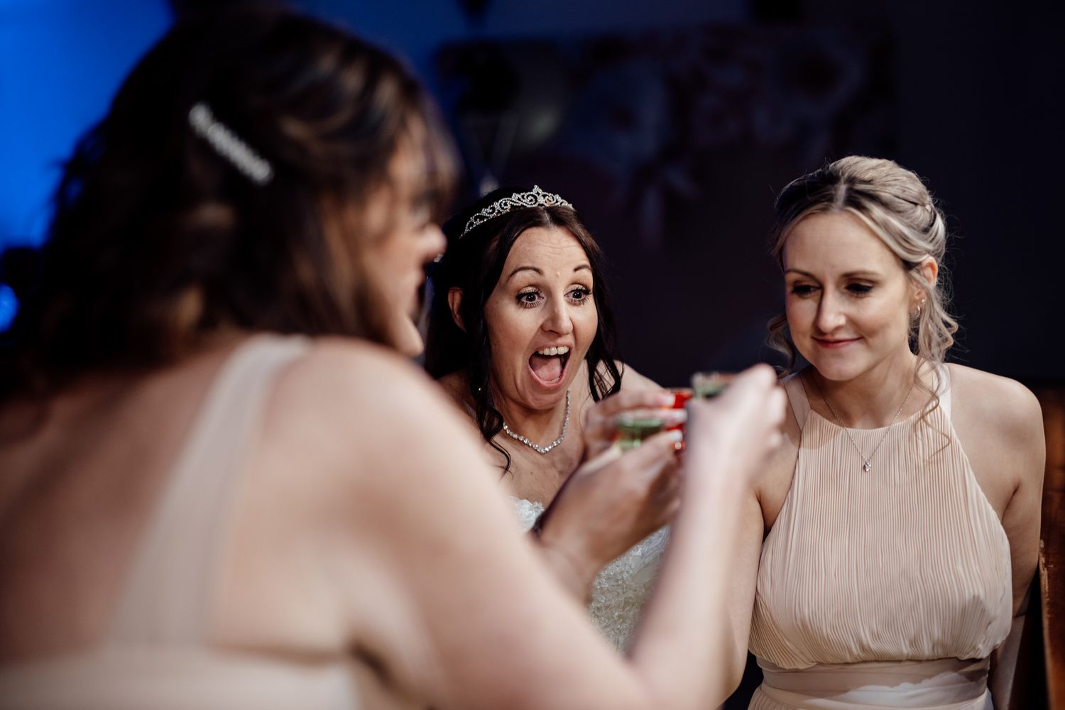 Candid moment of celebration during wedding reception with blue ambient lighting.