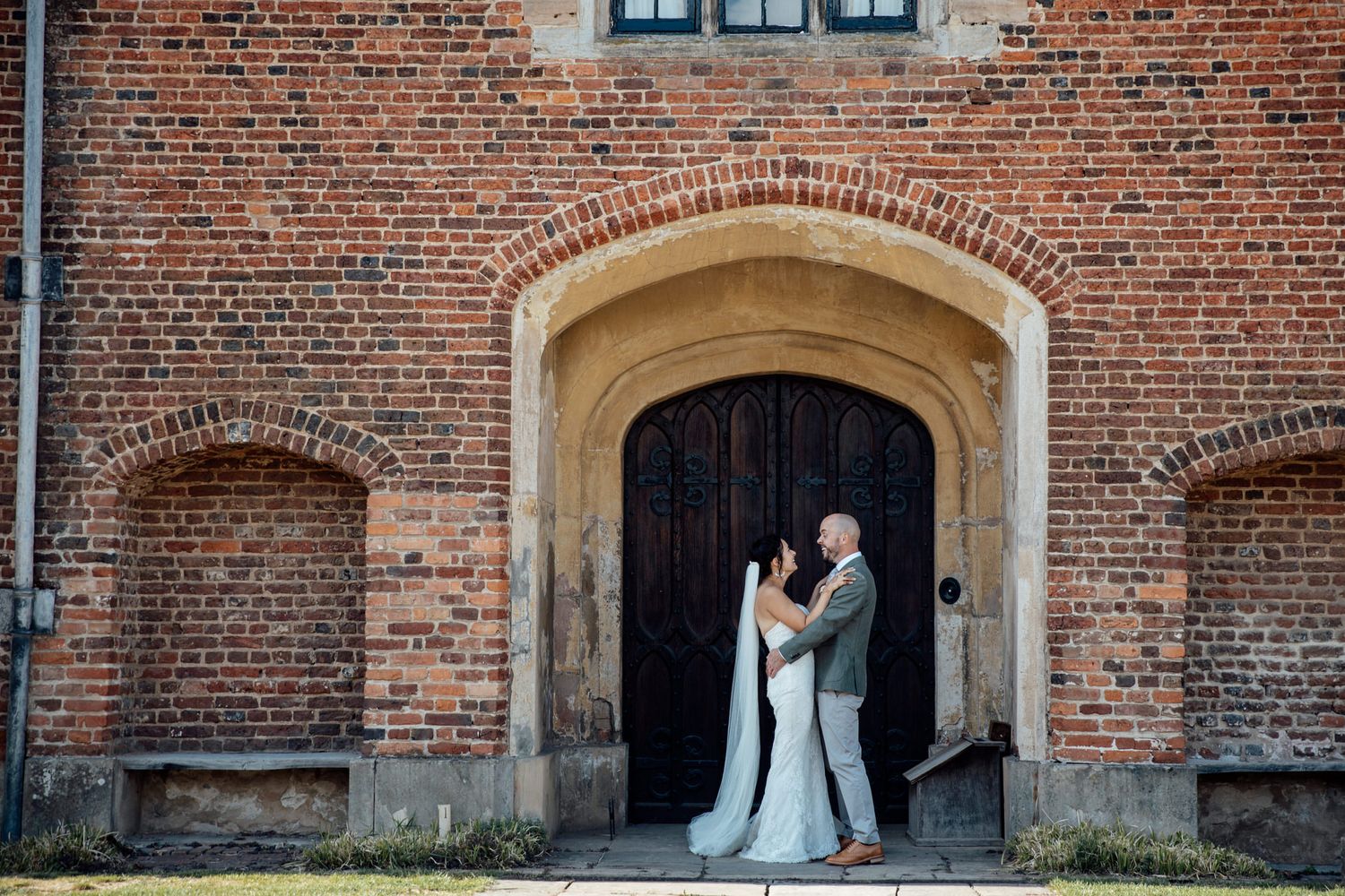 Historic brick building facade serves as backdrop for wedding portraits.