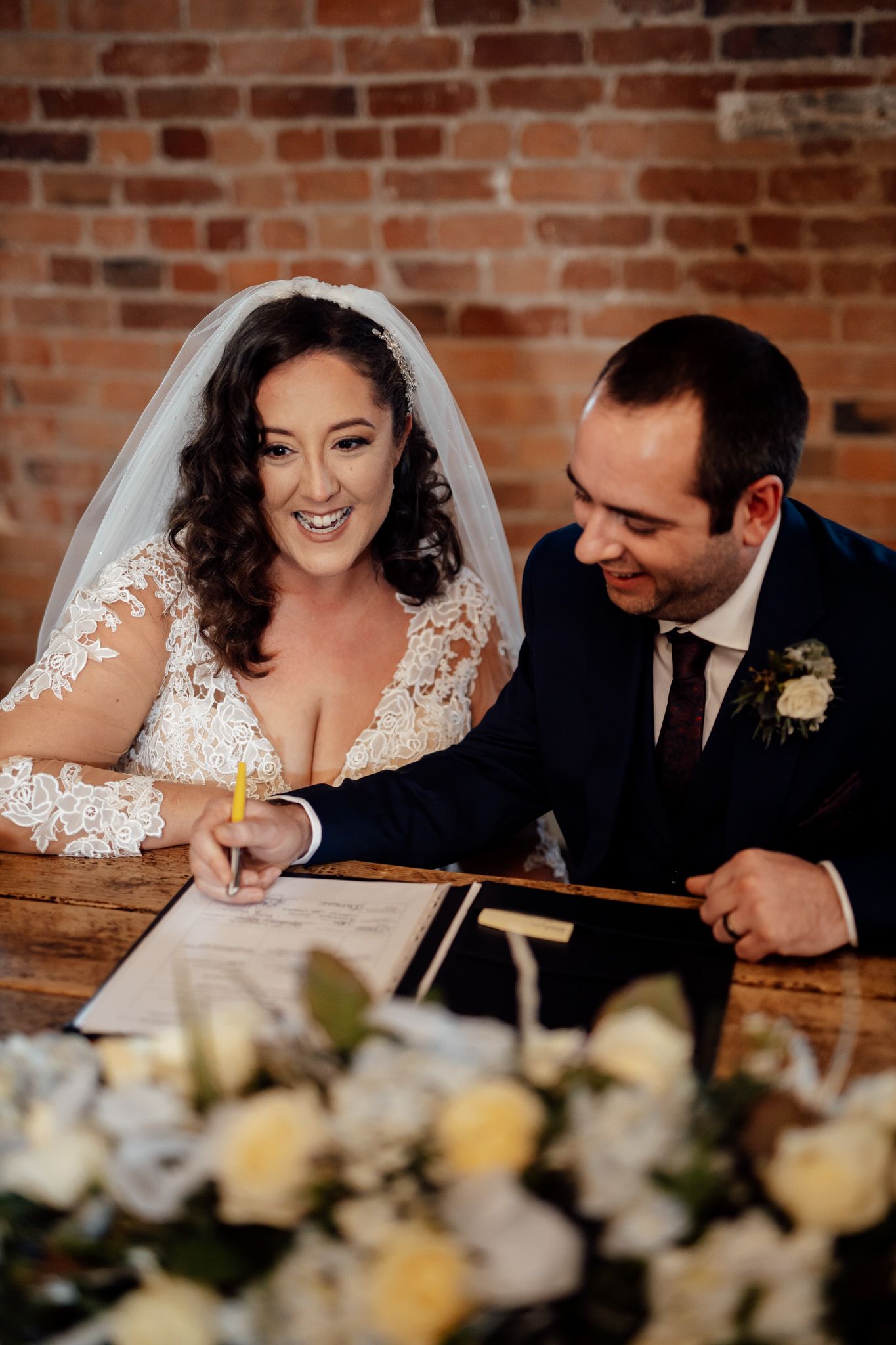 Wedding couple shares intimate moments at their reception table against exposed brick walls.
