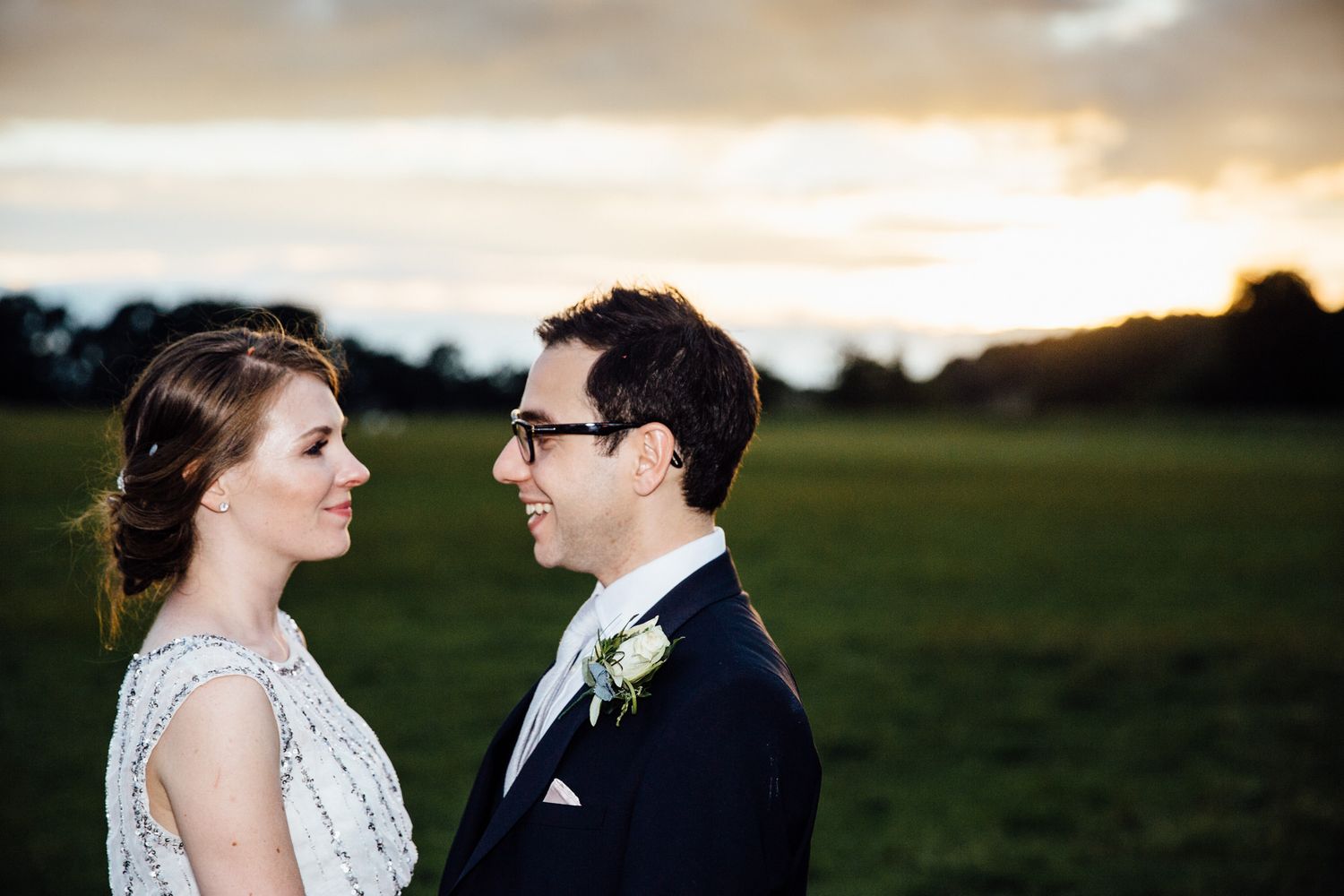 A romantic sunset portrait of newlyweds in an open field.