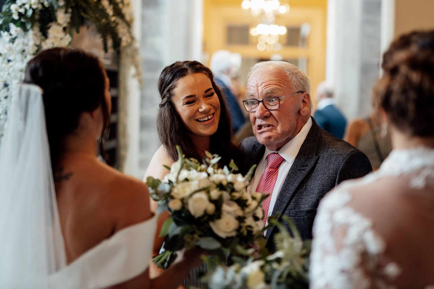 Wedding reception candid moments with elegant floral decorations and warm lighting.