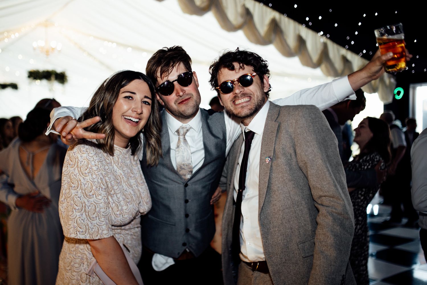 Wedding reception party with guests dancing under twinkling lights.