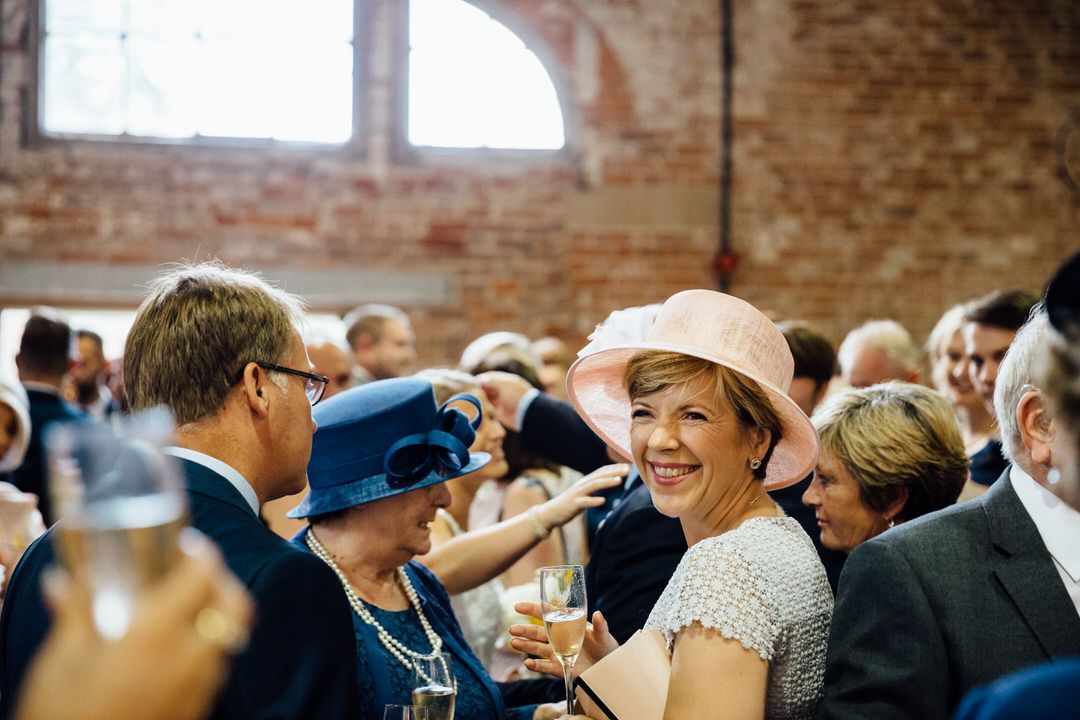 Wedding guests enjoying champagne and conversation at an indoor reception.