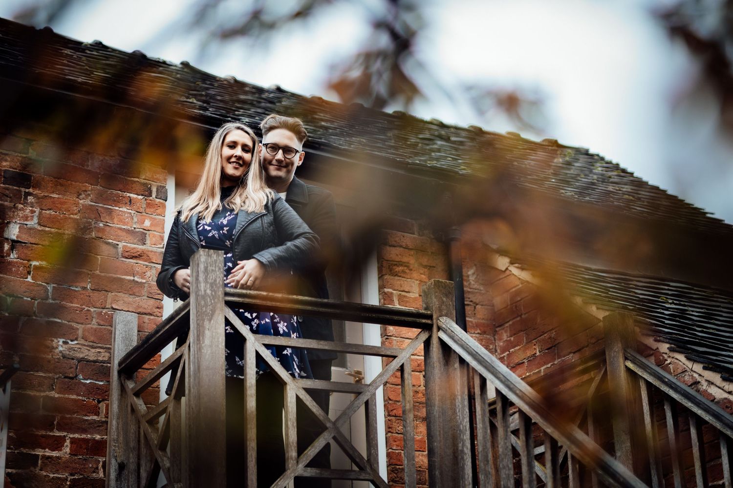 A couple embraces on rustic wooden stairs during an outdoor photo session.
