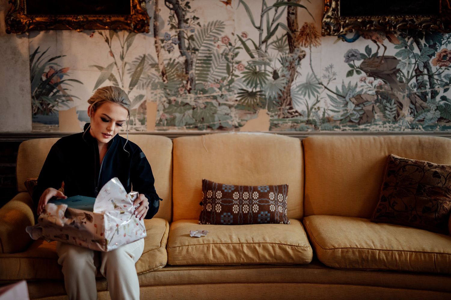 A relaxed scene on a vintage couch with decorative wallpaper featuring botanical designs.