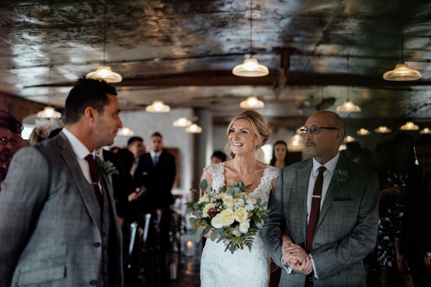 Wedding reception venue interior with hanging pendant lights and wooden beams.