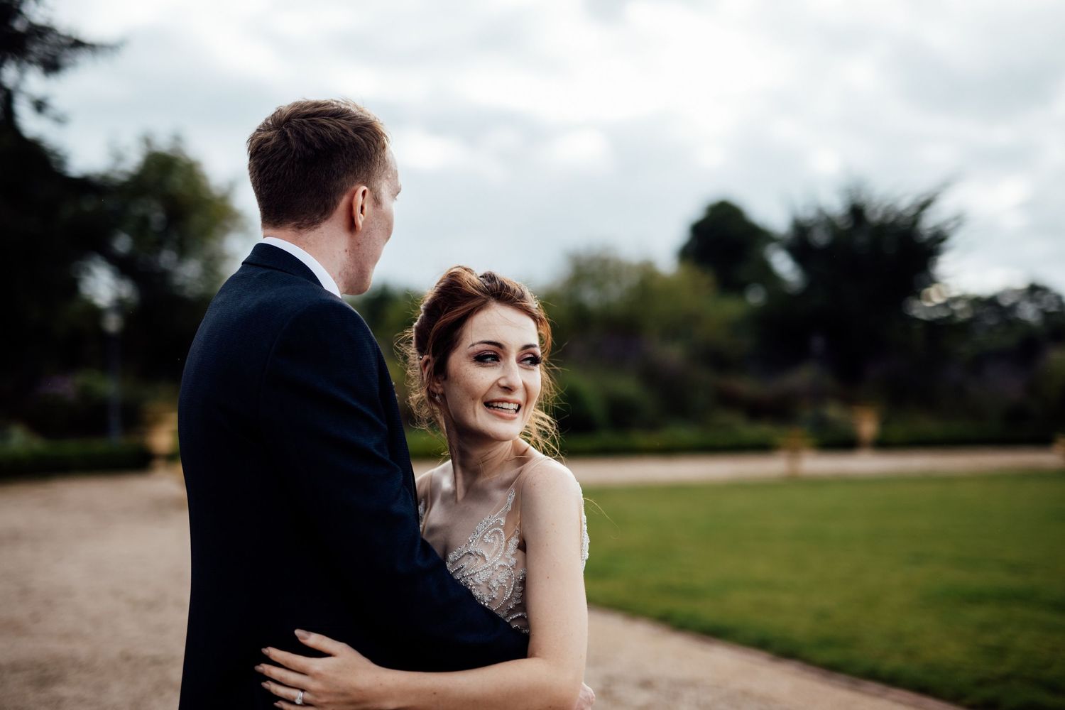 Wedding couple walking through countryside venue grounds on overcast day.