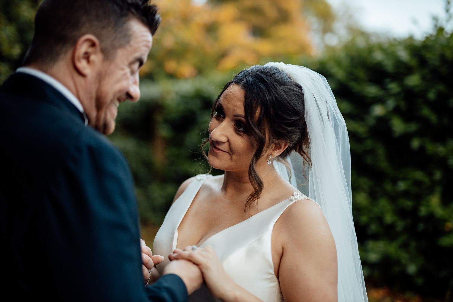 Candid wedding moments captured in a garden setting with natural autumn lighting.
