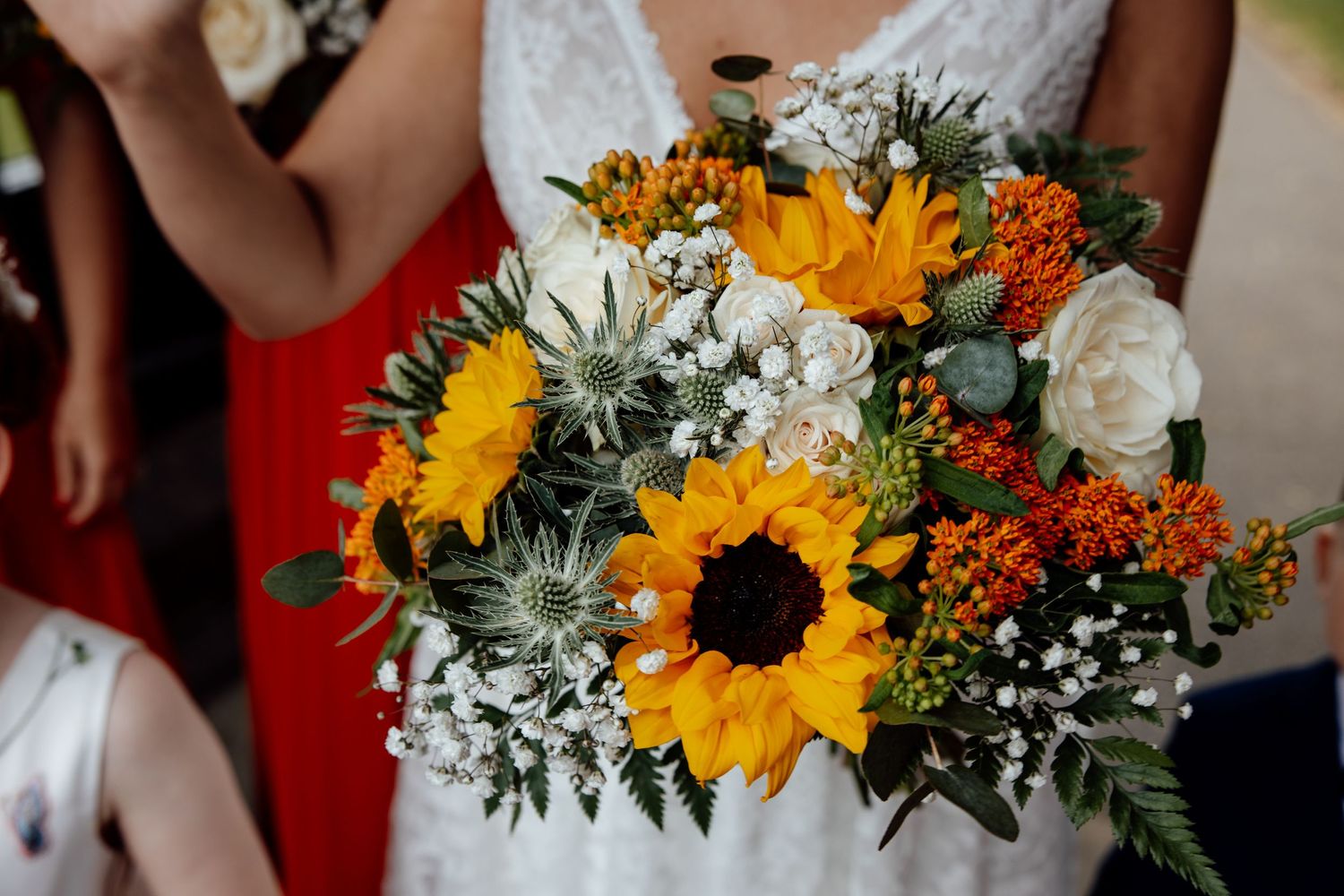 Vibrant wedding bouquet featuring sunflowers, white flowers, and greenery against a dark background.