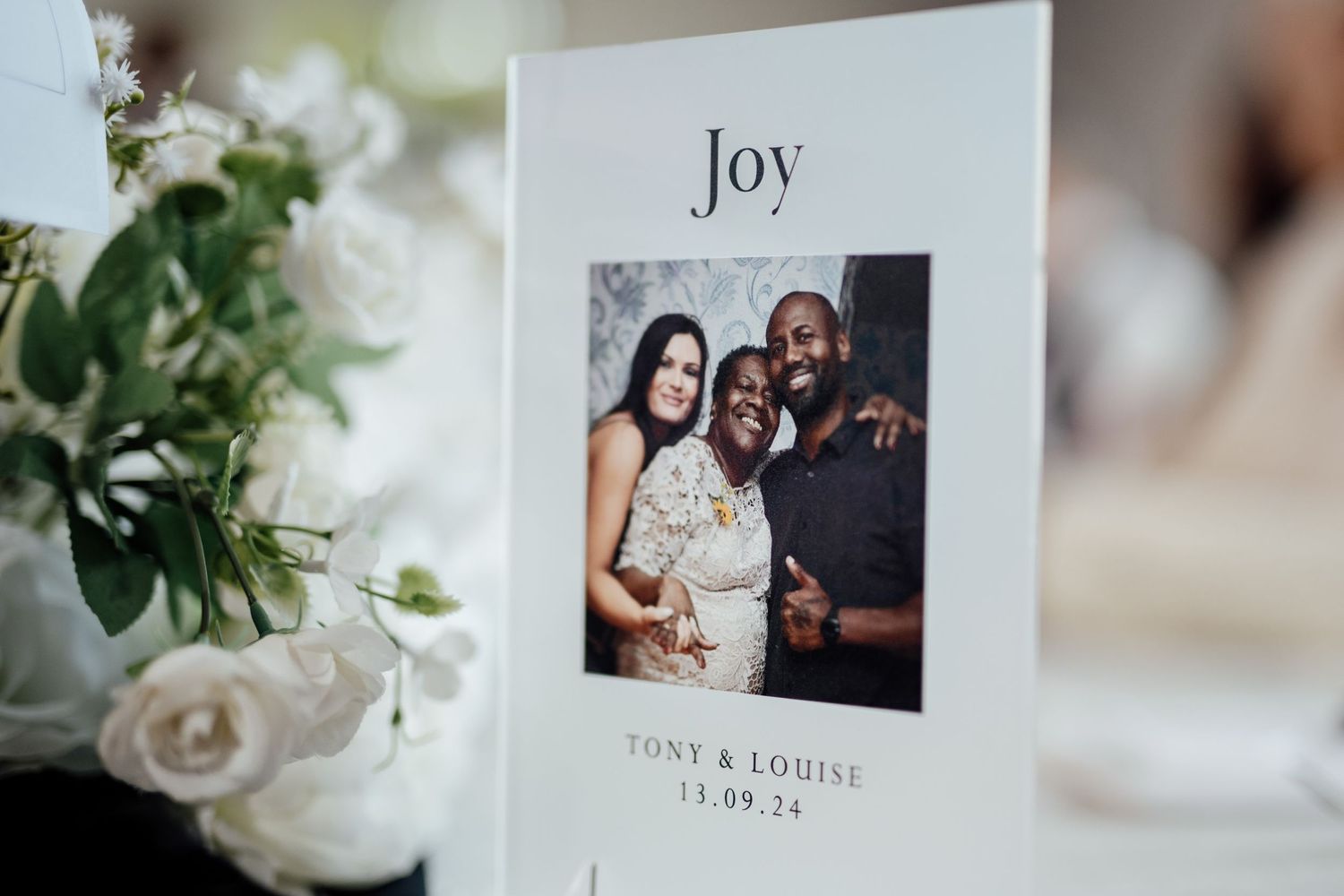 Elegant wedding stationery and decor featuring white roses and joy text.
