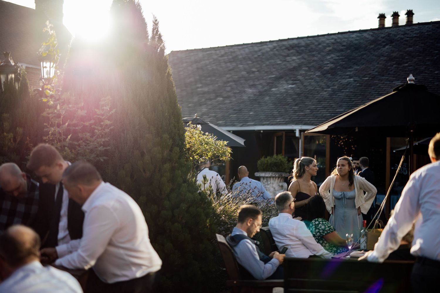 Wedding guests gather outdoors at sunset during a reception celebration.