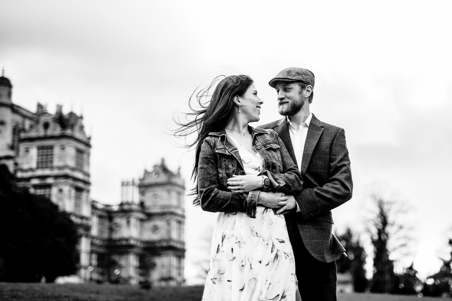 Romantic couple embracing against historic castle architecture backdrop.