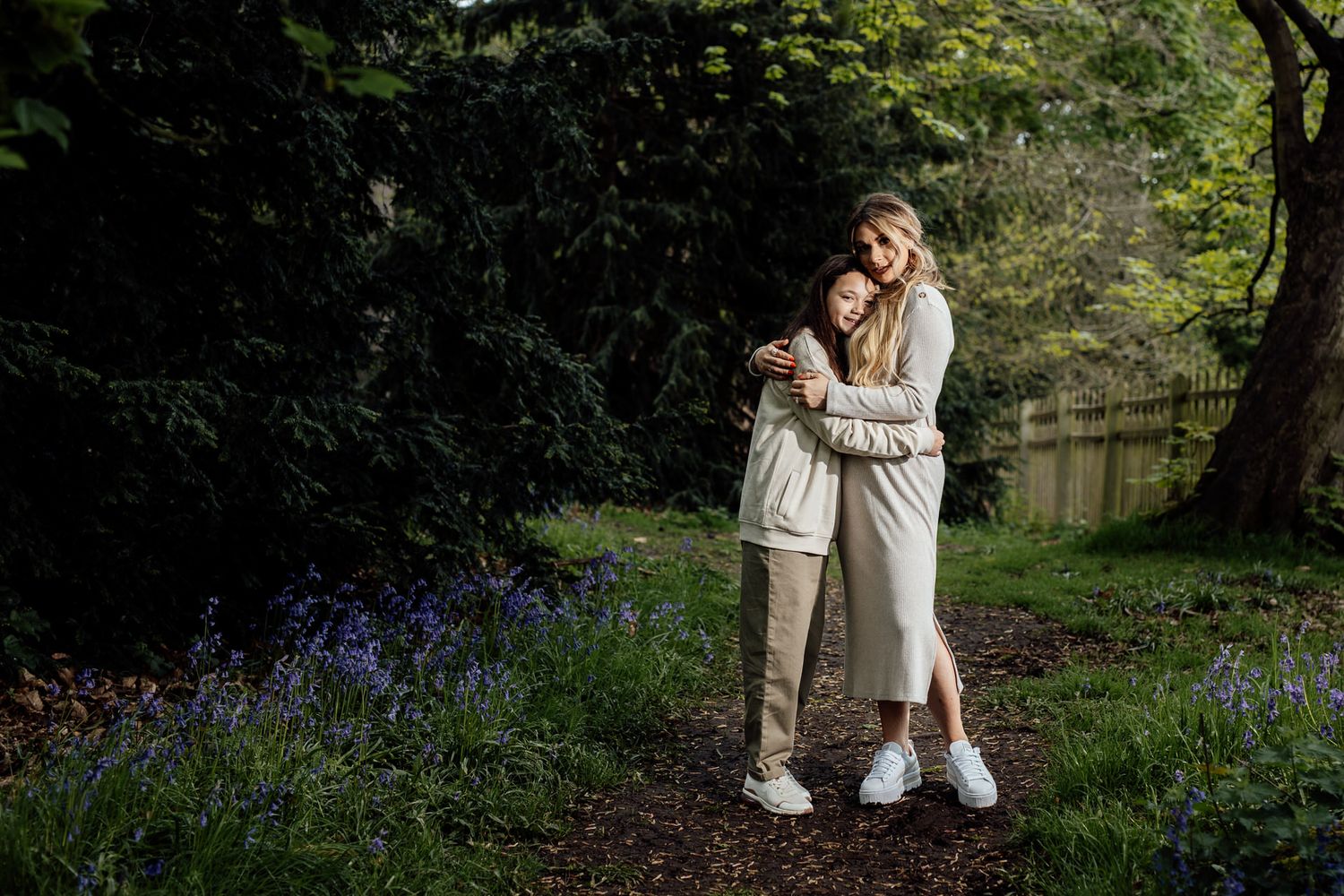 A family enjoys tender moments among blooming bluebells in a spring garden setting.