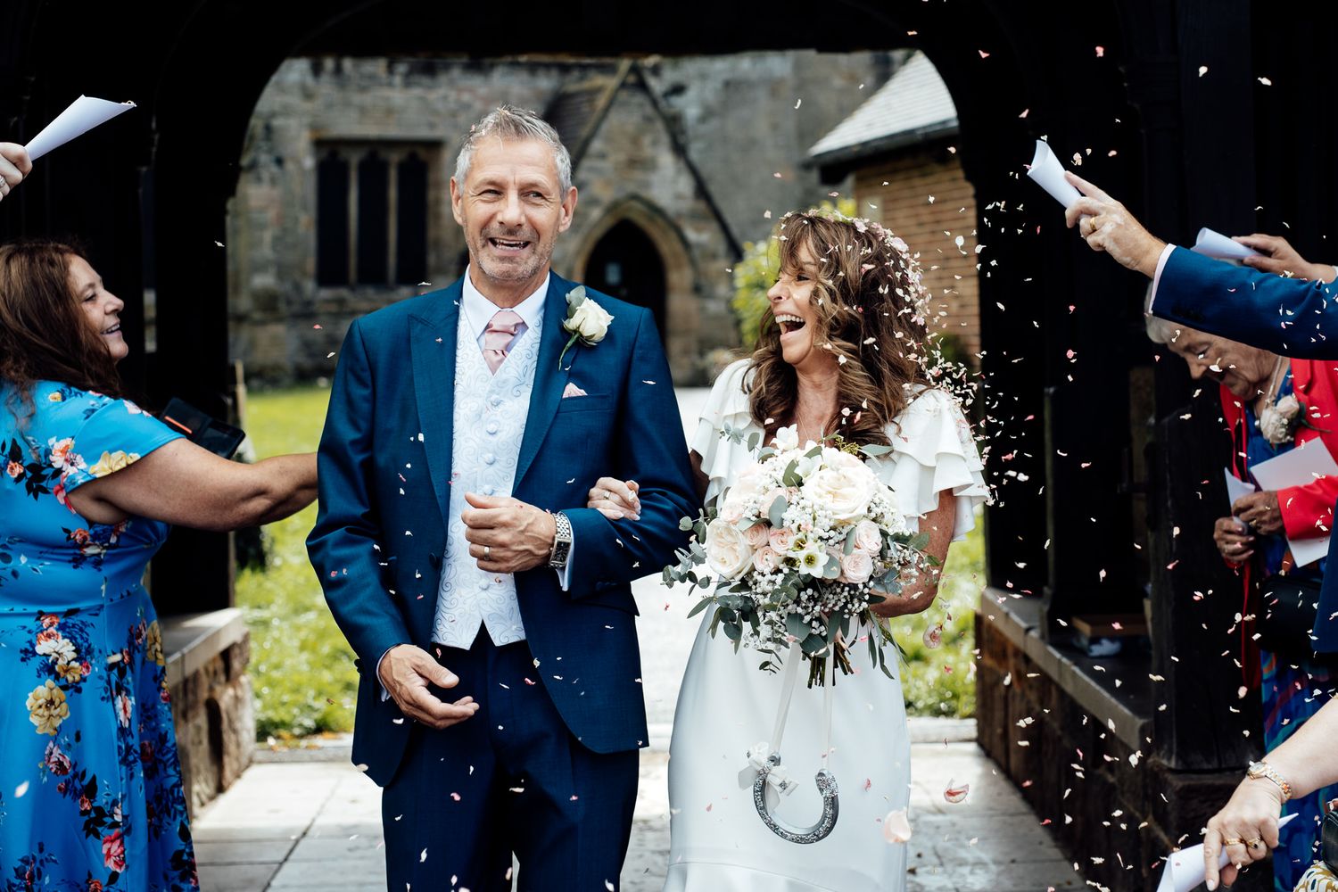 Wedding celebration with guests throwing confetti in outdoor setting.