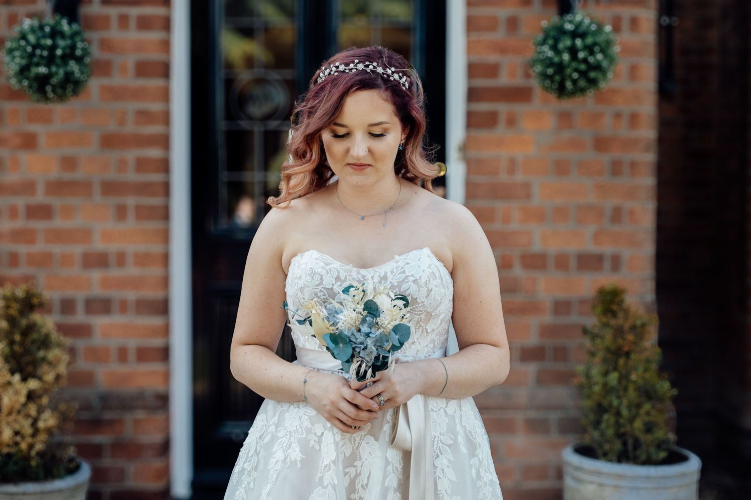 Close-up details of bridal gown with delicate lace against brick wall background.