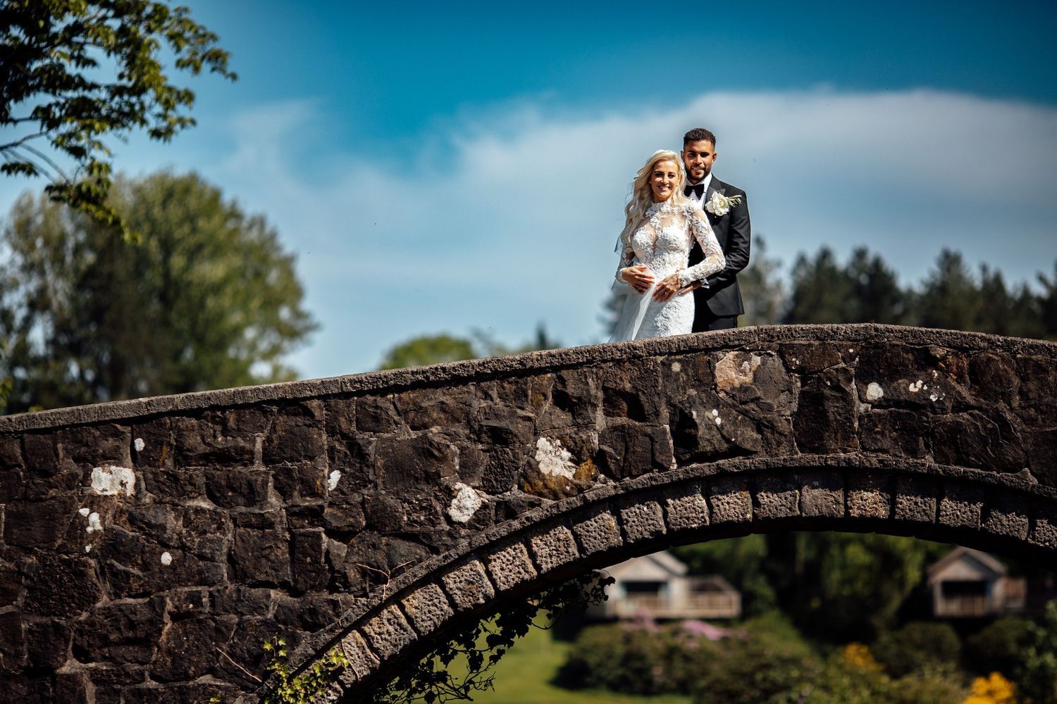 Stone bridge creates a romantic archway backdrop for outdoor wedding photography.
