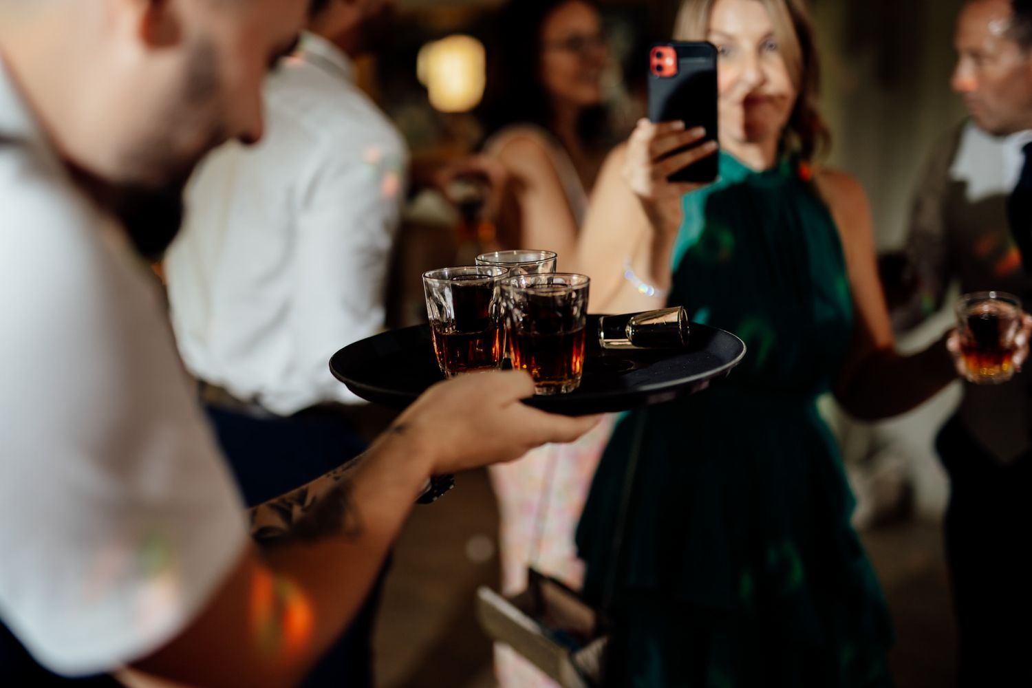Wedding guests enjoying drinks and celebrations in dimly lit venue.