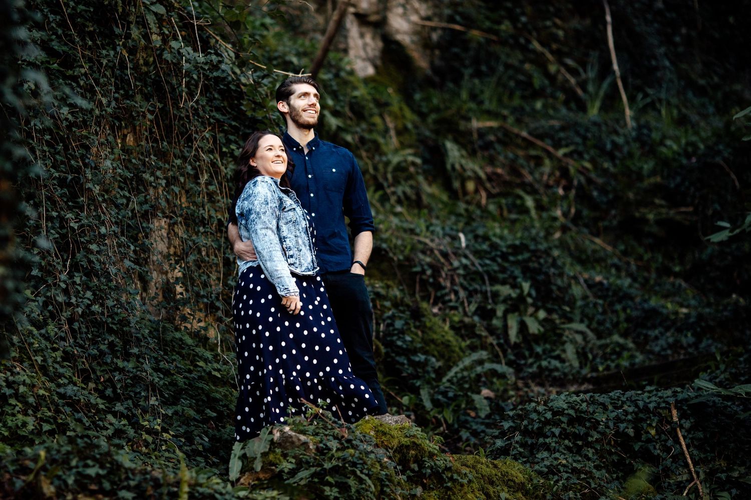 A romantic moment captured against a dark mossy natural backdrop.