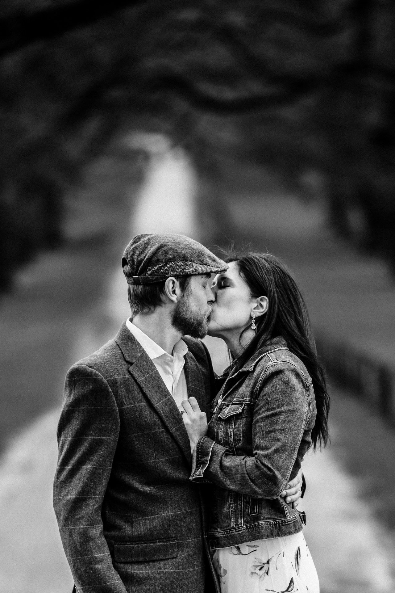 A romantic black and white portrait of a couple sharing an intimate moment in a park.