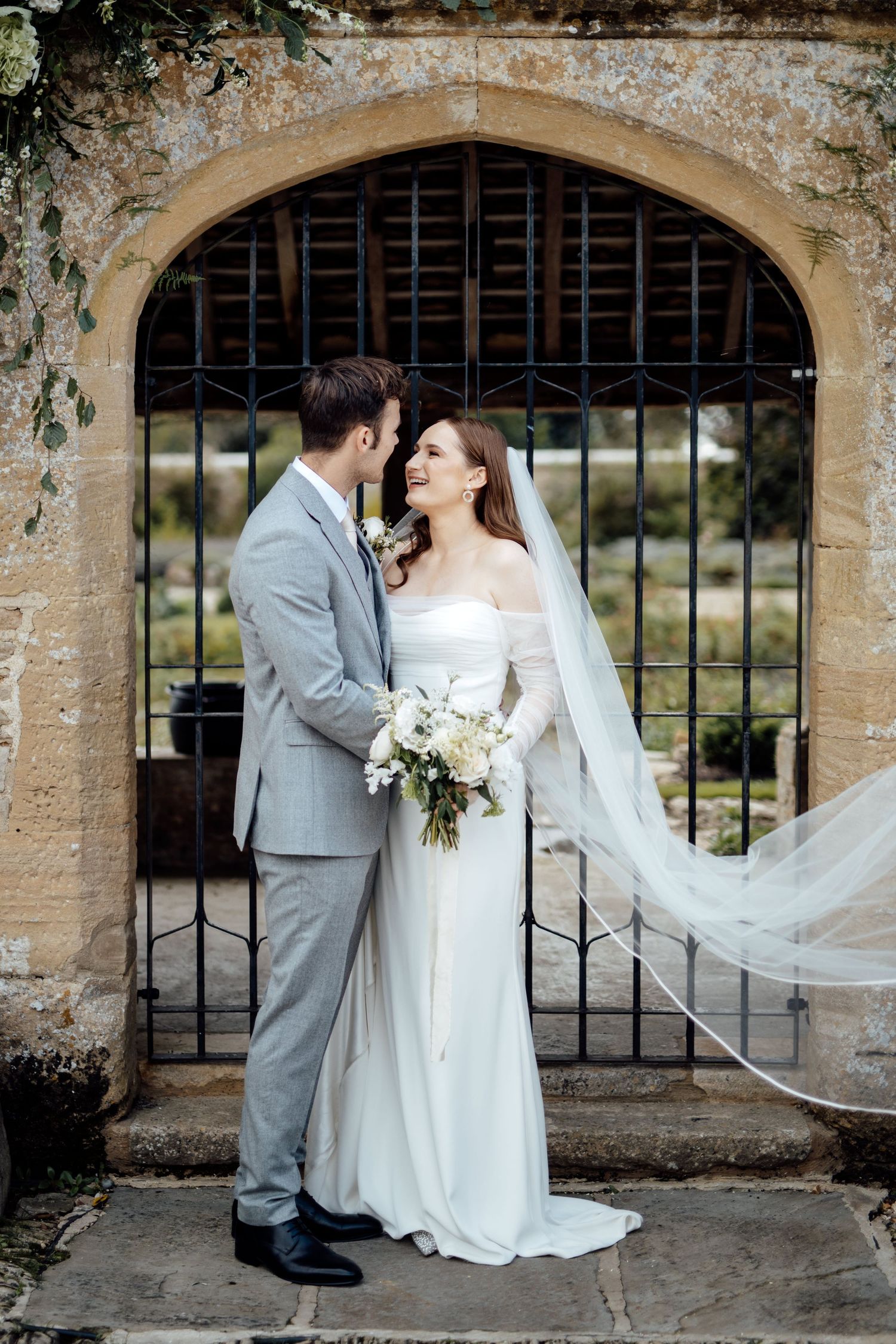 A couple poses for romantic portraits under stone archways at their wedding venue.