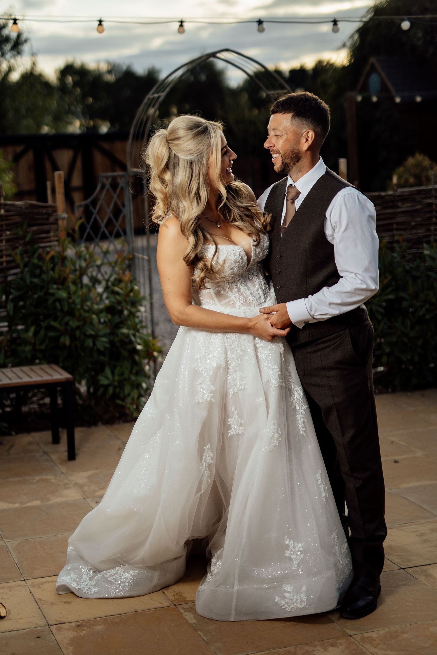 Bride and groom share a romantic dance outdoors at dusk after their wedding.