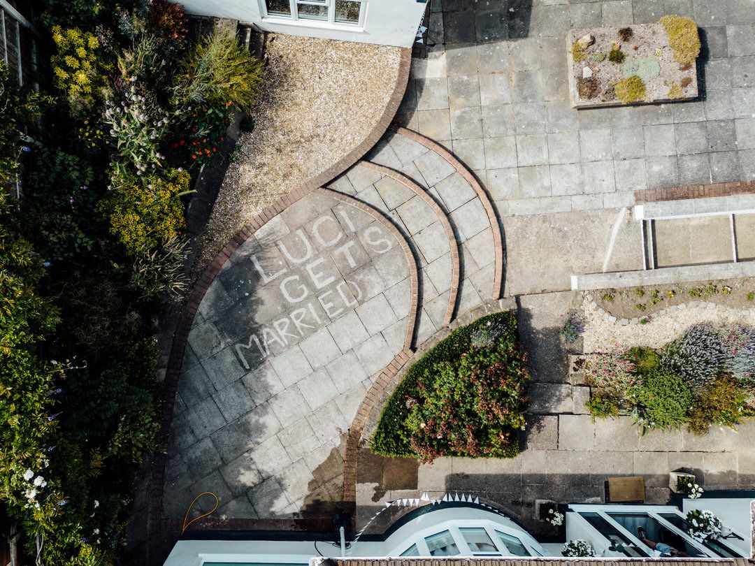Aerial view of curved stone pathway leading to entrance with landscaped gardens.