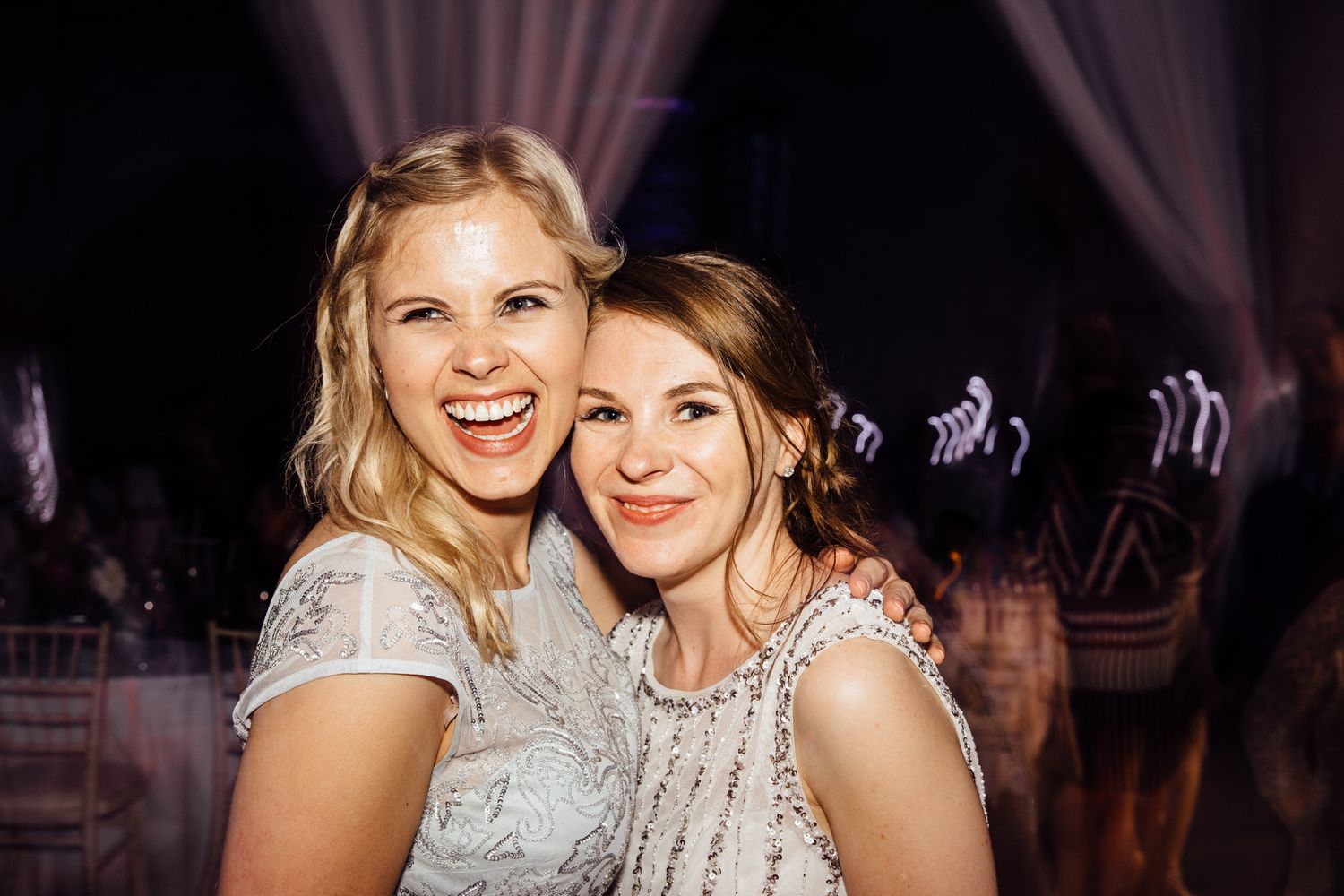 Guests smiling and embracing during an energetic wedding reception celebration.