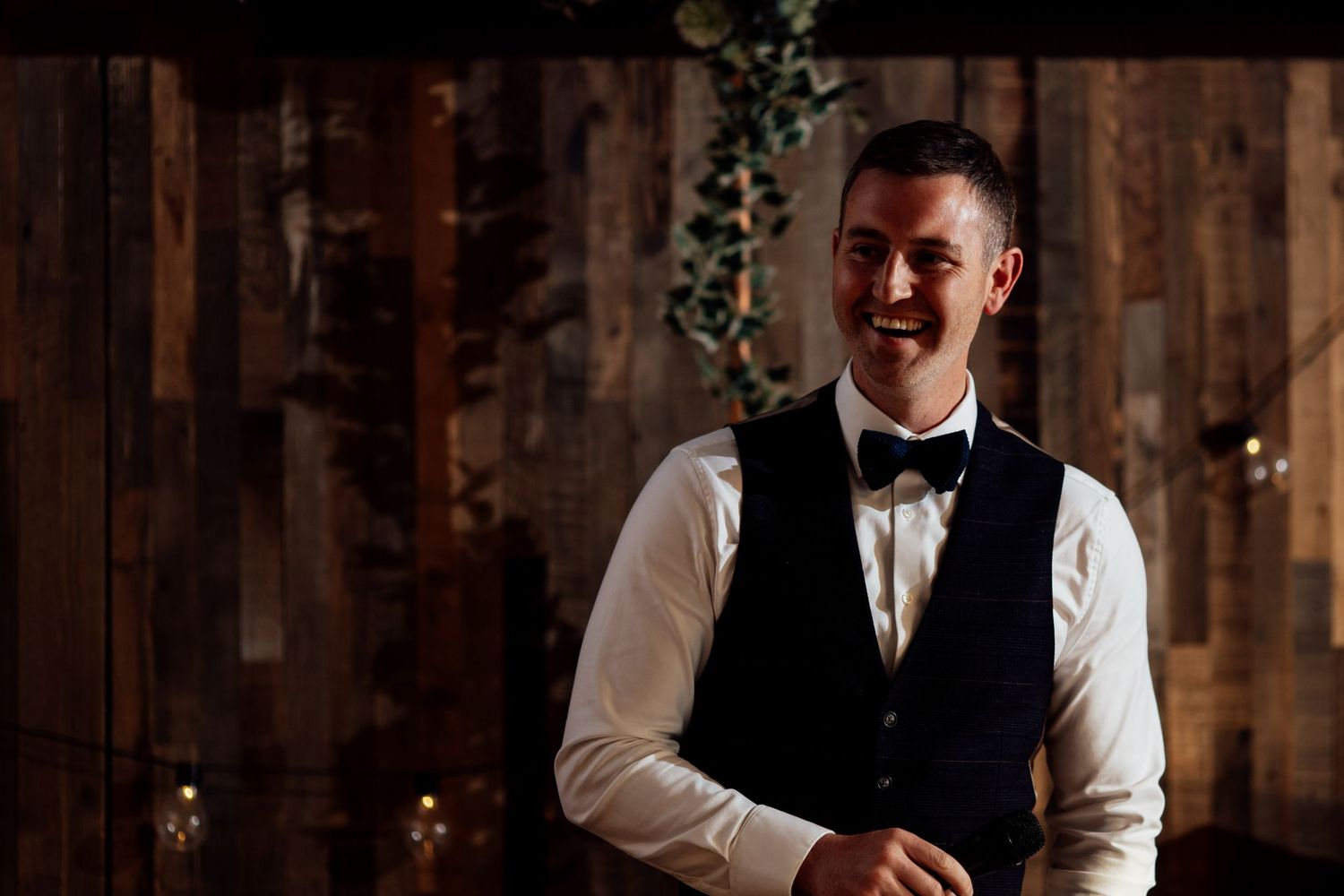 Reception celebration in a rustic barn venue with wooden walls and ambient lighting.
