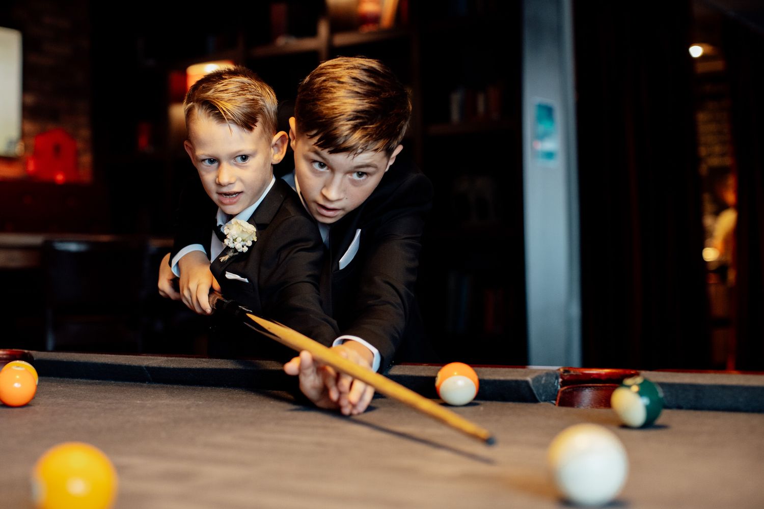 People playing pool in a dimly lit entertainment venue.