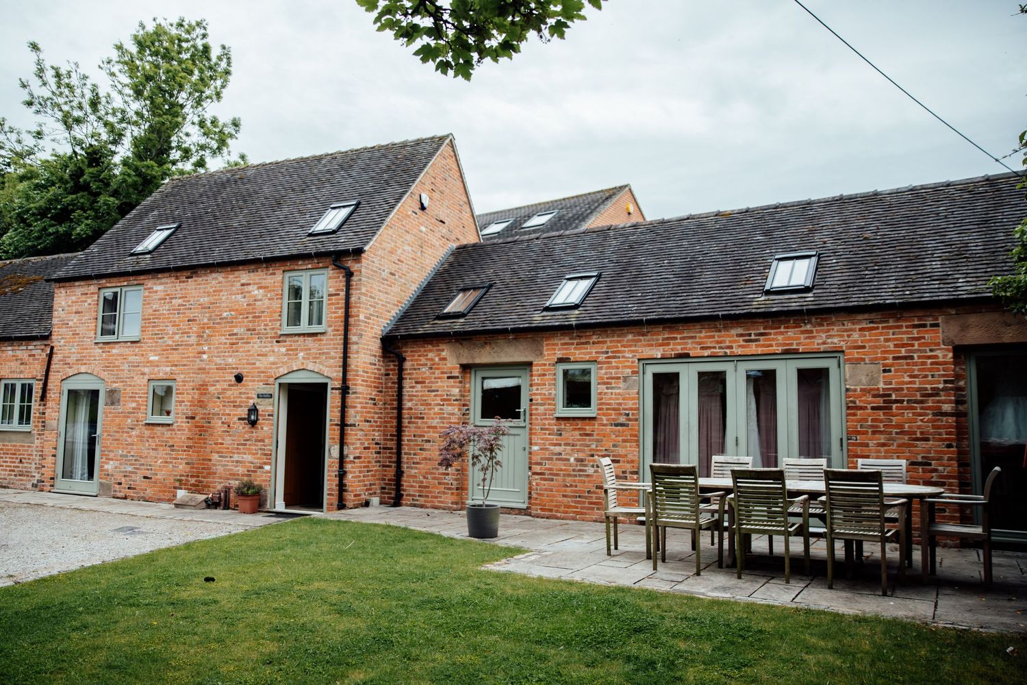 Exterior view of converted barn wedding venue with red brick walls and landscaping.