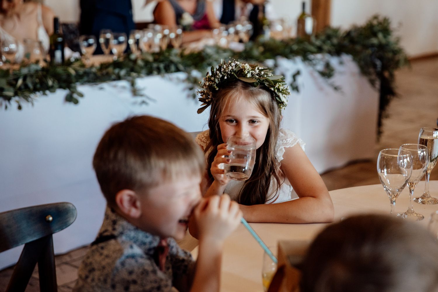 Wedding reception candid moment with children enjoying drinks at decorated table.