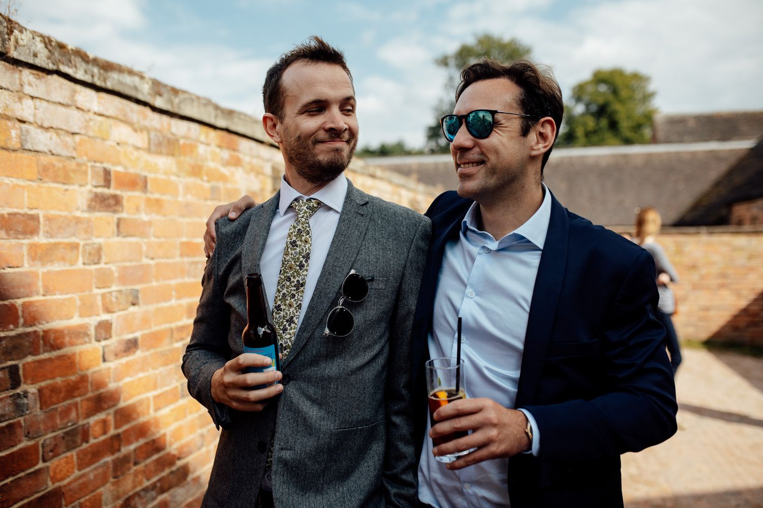 Groomsmen sharing laughs and drinks during outdoor wedding celebrations.