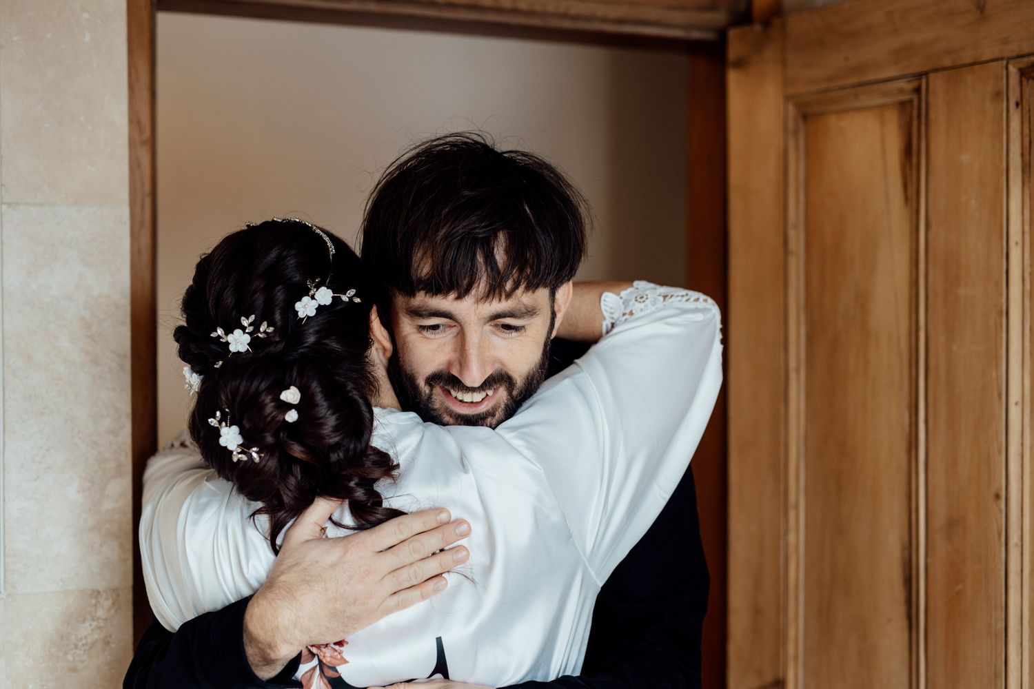 Intimate moment captured in doorway with natural lighting and white floral details.