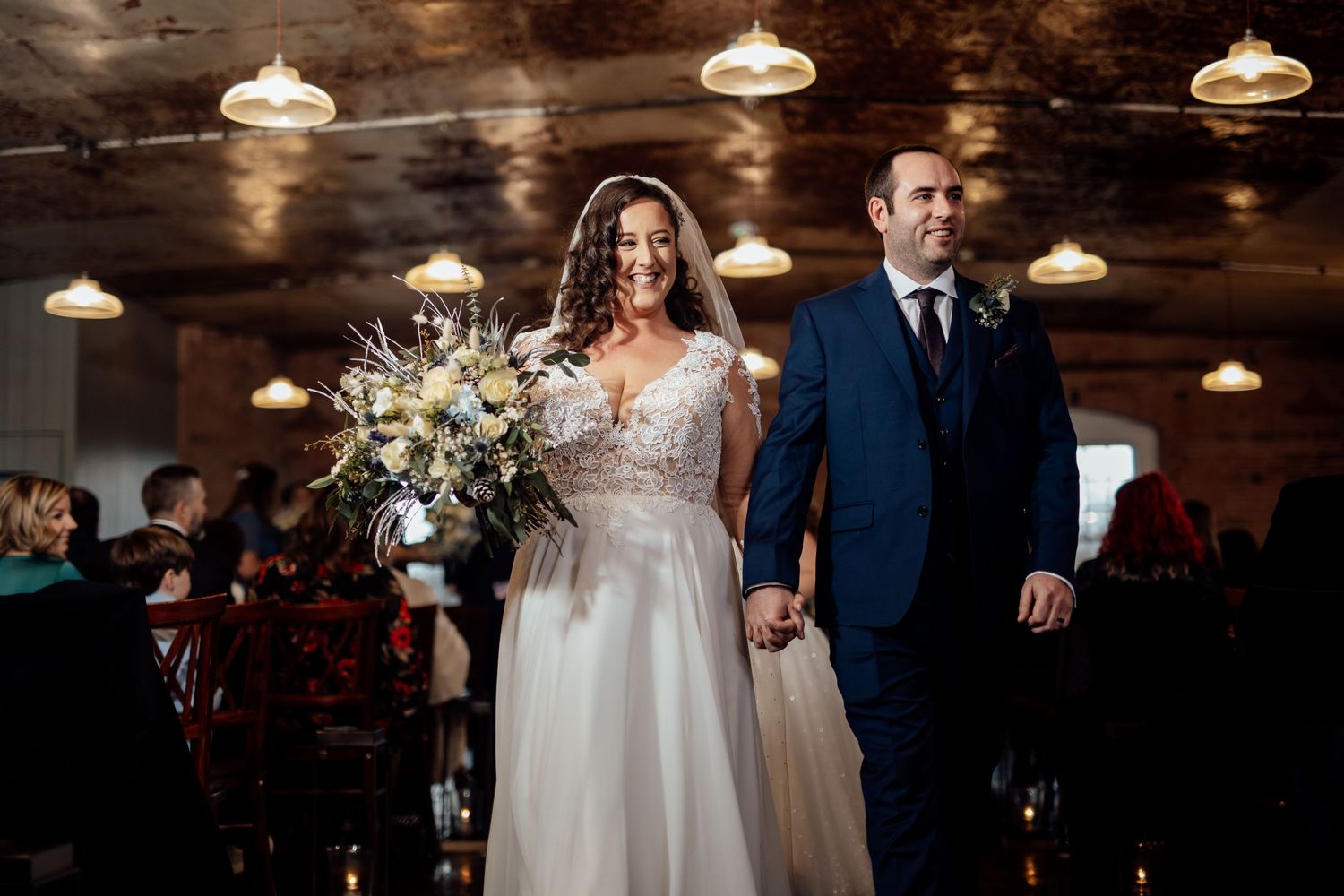Wedding reception in a rustic venue with warm pendant lighting and exposed brick walls.
